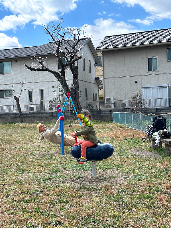 At a playground in Tsuruga, Fukui. Kevin is hanging from a set of bars, Aki is riding on a grub-like thing