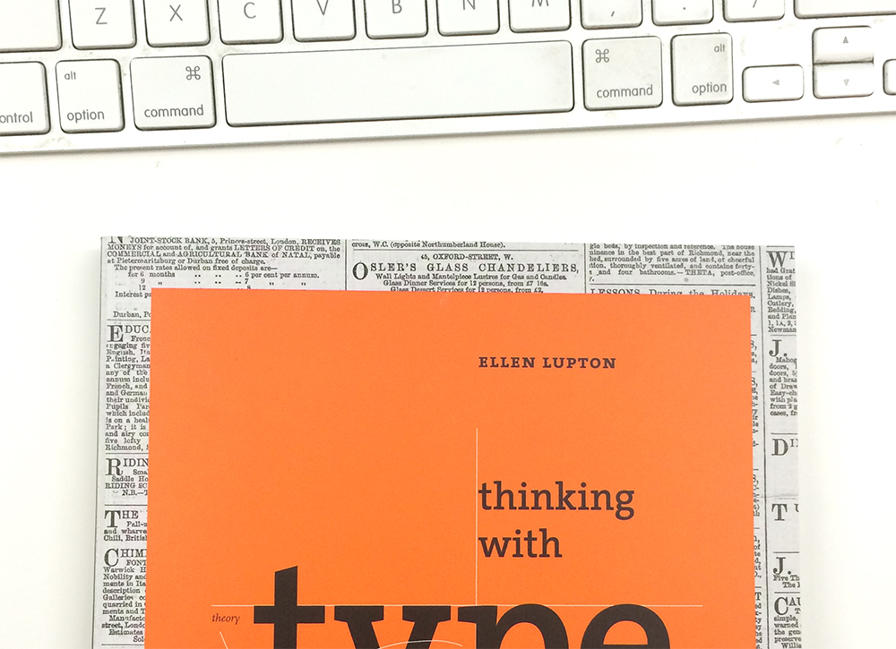 A photo of Ellen Lupton’s book Thinking with Type peeking out from the bottom on a white table.