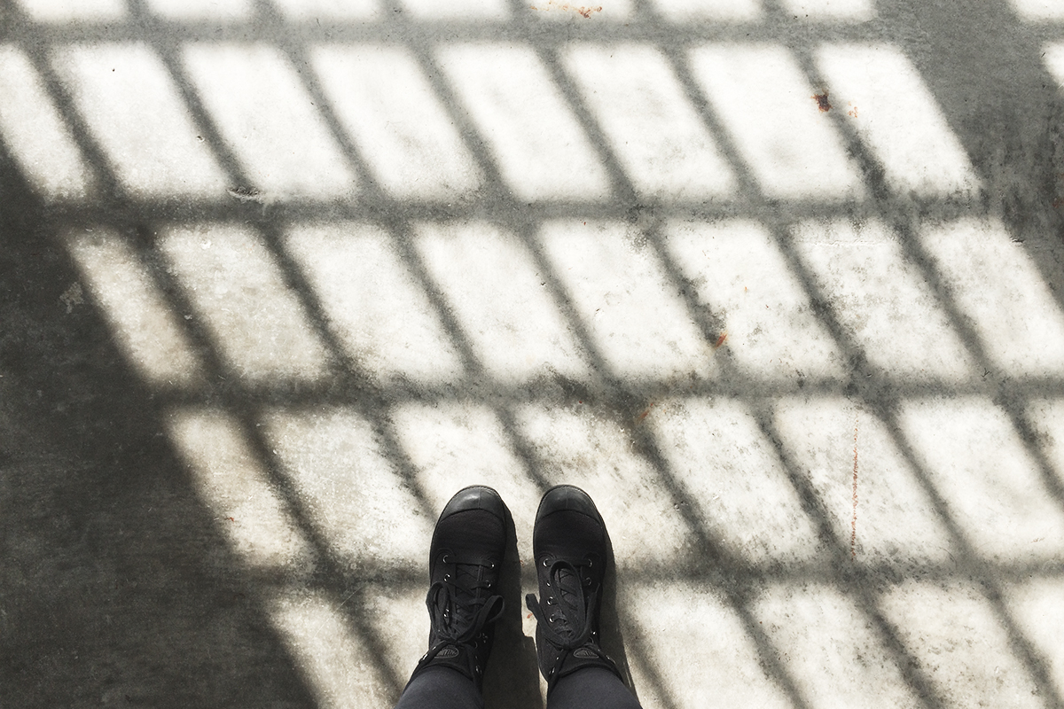 Photo of my feet on the floor of Alcatraz, the window pane casting a shadow