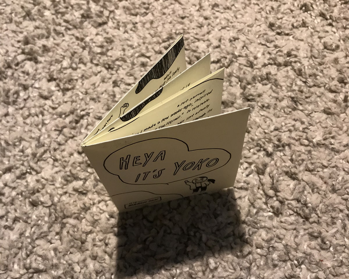 Photo of the zine, placed upright on a carpet and shot from the top. It’s about 3.5 inches wide by 4.25 inches tall, and has a cover and 3 spreads.
